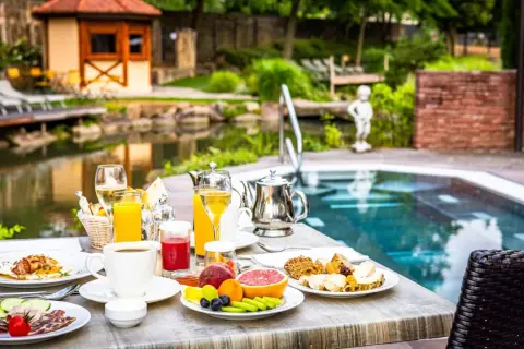 Petit-déjeuner copieux au domaine Moulin Ensisheim, avec vue sur la piscine et le jardin.