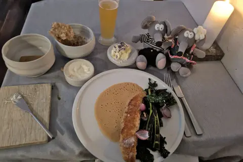 Un dîner romantique dans un restaurant de Copenhague pas cher. Deux souris en peluche observent un plat de poisson, des légumes et une mousse.