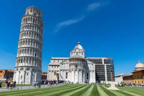 La célèbre tour de Pise, penchée et majestueuse, se dresse fièrement sous un ciel bleu éclatant, à côté de la cathédrale.