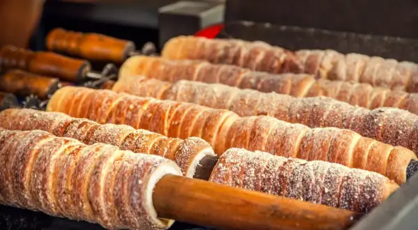 Trdelník, un délicieux dessert tchèque, cuit sur des broches en bois, saupoudré de sucre.