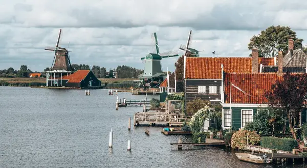 Moulins à vent et maisons traditionnelles au bord de l'eau, un paysage typique pour savoir quoi visiter en Hollande.