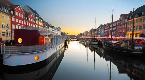 Canal de Nyhavn à Copenhague au coucher du soleil, avec des maisons colorées et des bateaux. Parfait pour un week-end copenhague.