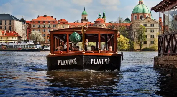 Une croisière à Prague sur le bateau "Plavuně" offre une vue magnifique sur les bâtiments historiques et les dômes verts.