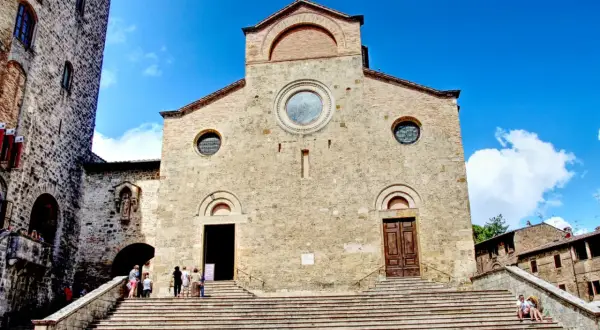 Le majestueux **duomo San Gimignano** se dresse sous un ciel bleu éclatant, ses marches invitant à la découverte de son histoire.