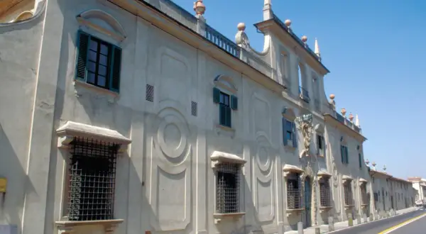 Façade d'une villa à Sesto Fiorentino, avec des fenêtres à volets verts et des ornements circulaires sur le mur.