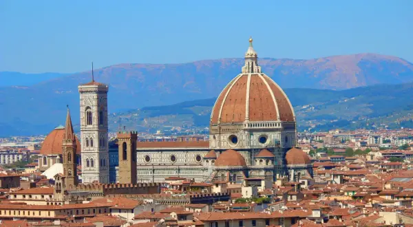 La célèbre coupole de Florence domine la ville, avec son campanile et ses toits de tuiles rouges sous un ciel bleu.