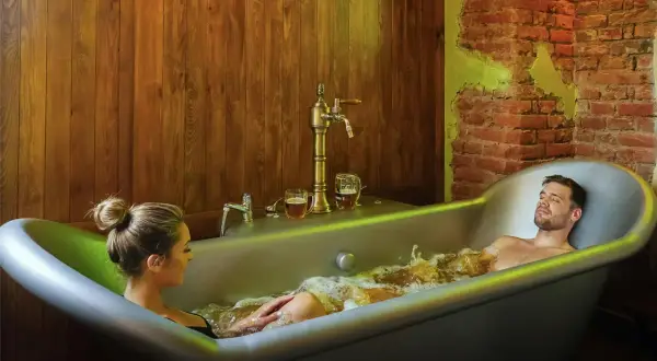 Un couple profite d'un bain bière à Prague, avec des chopes de bière à portée de main.