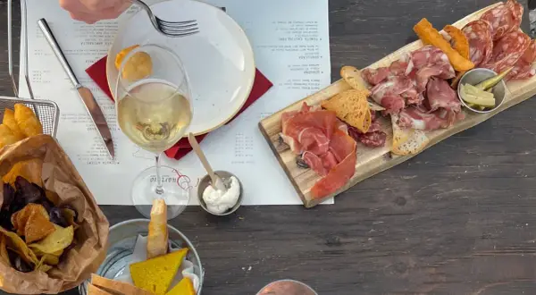 Assiette de charcuterie et de fromage, vin blanc, chips et pain, dans un vignoble de la province de Grosseto.