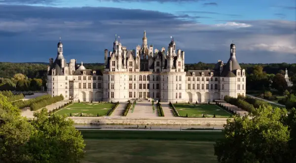 Le majestueux château de Chambord se dresse, avec ses tours et ses toits complexes, sous un ciel dramatique.