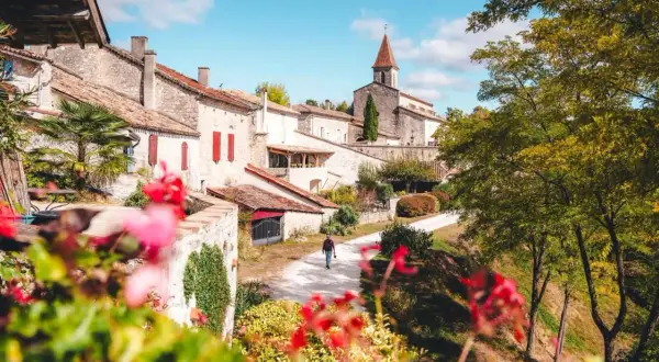 Un homme marche dans un village pittoresque, parmi les plus beaux villages du Tarn-et-Garonne. L'église domine le paysage.