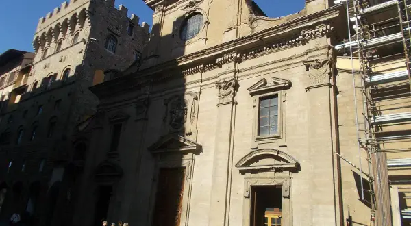 Façade de la basilique Santa Trinita à Florence, avec des échafaudages sur le côté droit. Des vélos sont garés devant.