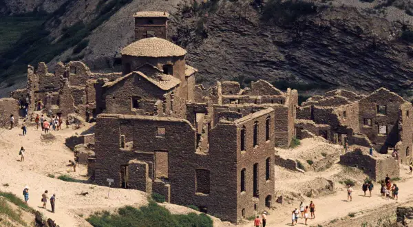 Ruines de pierre du lago di vagli, un village fantôme envahi par la végétation, avec des visiteurs explorant les vestiges.