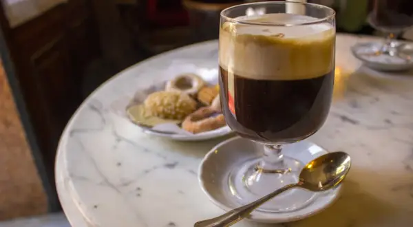 Un café viennois et des biscuits sur une table en marbre, une invitation à découvrir où manger à Turin.