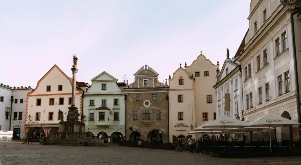 Place de la ville pavée avec une colonne baroque et des maisons colorées, parfait pour visiter la République Tchèque.