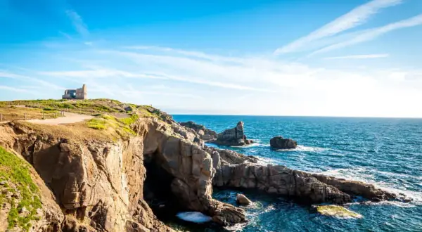 Falaises rocheuses et ruines d'un bâtiment sur une colline surplombant la mer bleue. Idéal pour savoir que faire à Quiberon ce week-end.