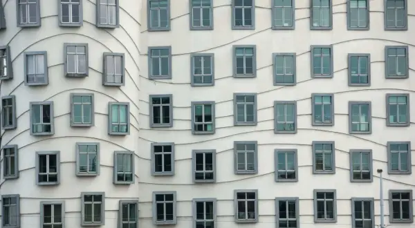 La façade ondulée de la Dancing House à Prague, avec ses fenêtres grises disposées en rangées, semble danser sous le ciel.