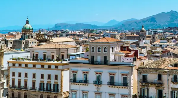 Vue panoramique de Palerme, avec ses bâtiments historiques et ses dômes sous un ciel bleu. Parfait pour un week-end à Palerme.