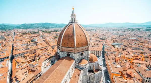 Vue aérienne de Florence, avec le dôme de Brunelleschi dominant la ville. Les toits de tuiles orangées s'étendent à perte de vue.
