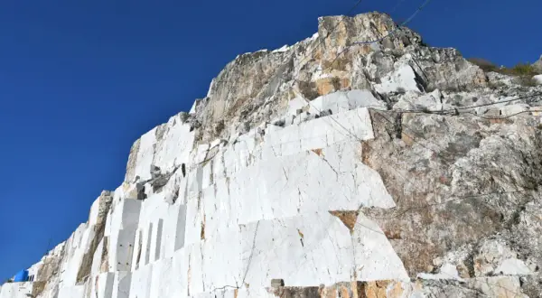 Carrières de marbre blanc à Carrare, Italie, sous un ciel bleu intense. Les blocs taillés révèlent la beauté brute de la roche.