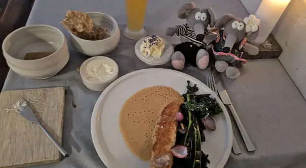 Un dîner romantique dans un restaurant de Copenhague pas cher. Deux souris en peluche observent un plat de poisson, des légumes et une mousse.