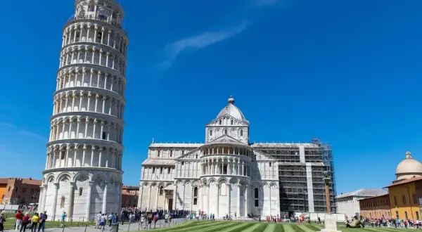 La célèbre tour de Pise, penchée et majestueuse, se dresse fièrement sous un ciel bleu éclatant, à côté de la cathédrale.