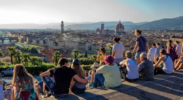 Vue panoramique de Florence depuis le Piazzale Michelangelo. Des touristes profitent du coucher de soleil sur la ville.