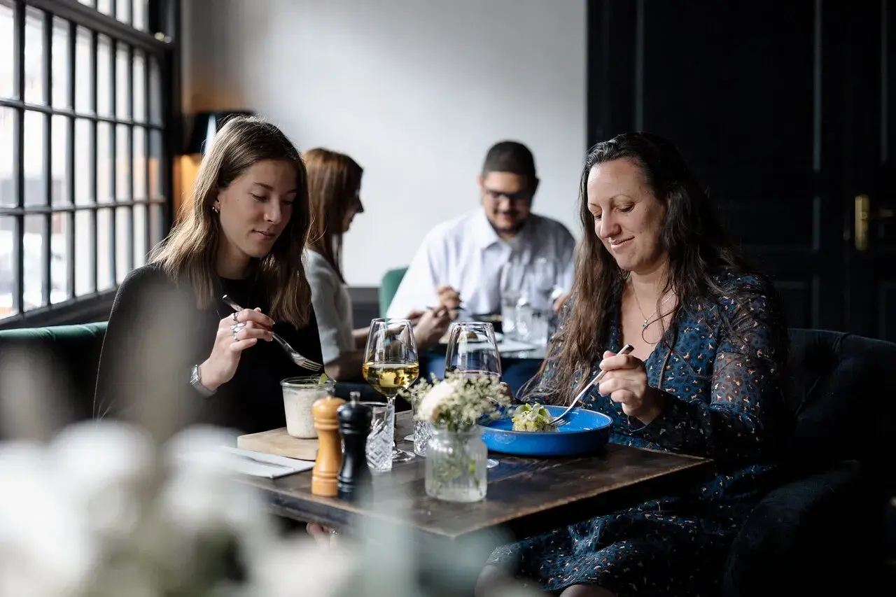 Ambiance chaleureuse pour savoir où manger à Honfleur. Quatre personnes savourent un repas dans un restaurant cosy.