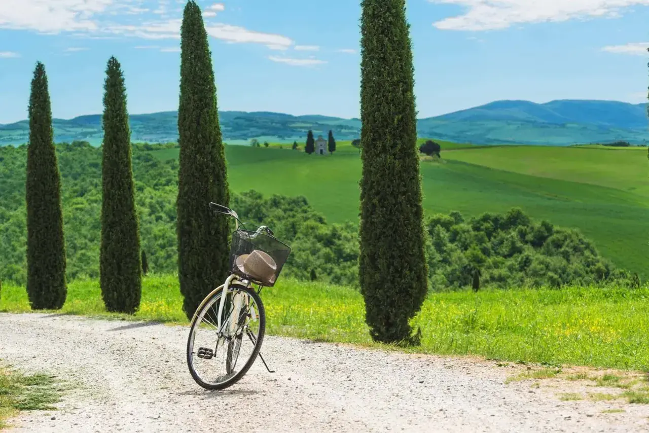 Vélo prêt pour une exploration de la Toscane à vélo, avec des cyprès élancés et des collines verdoyantes en arrière-plan.