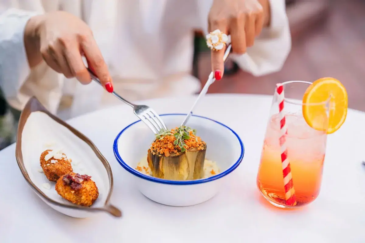 Un plat d'artichaut garni, des croquettes et un cocktail fruité dans un restaurant à Grenade.
