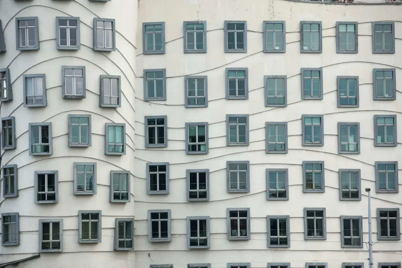 La façade ondulée de la Dancing House à Prague, avec ses fenêtres grises disposées en rangées, semble danser sous le ciel.