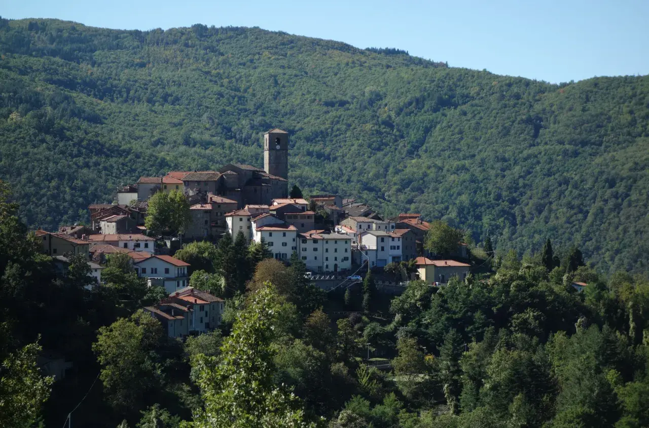 Village de San Marcello Pistoiese niché sur une colline verdoyante, avec son clocher dominant les toits de tuiles rouges.