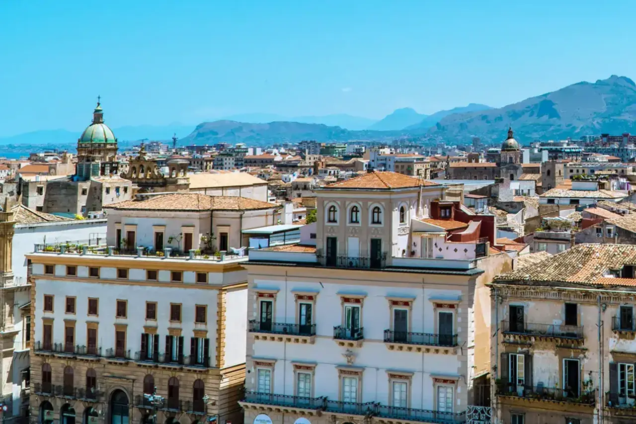 Vue panoramique de Palerme, avec ses bâtiments historiques et ses dômes sous un ciel bleu. Parfait pour un week-end à Palerme.