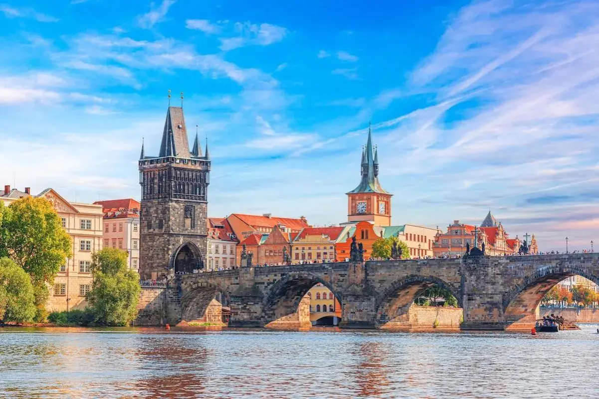 Le pont Charles et la tour de la Vieille Ville, témoins de la riche prague histoire, se reflètent dans la Vltava sous un ciel bleu.