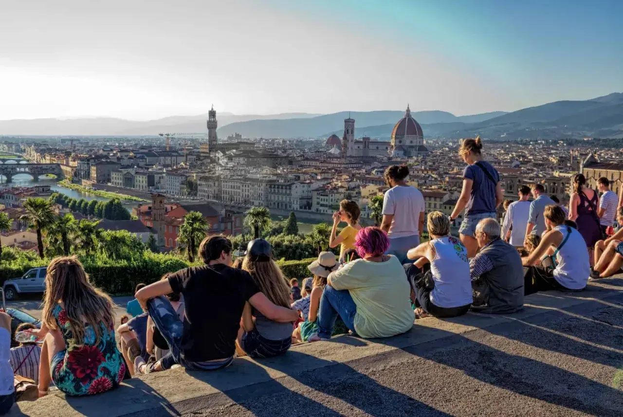 Vue panoramique de Florence depuis le Piazzale Michelangelo. Des touristes profitent du coucher de soleil sur la ville.
