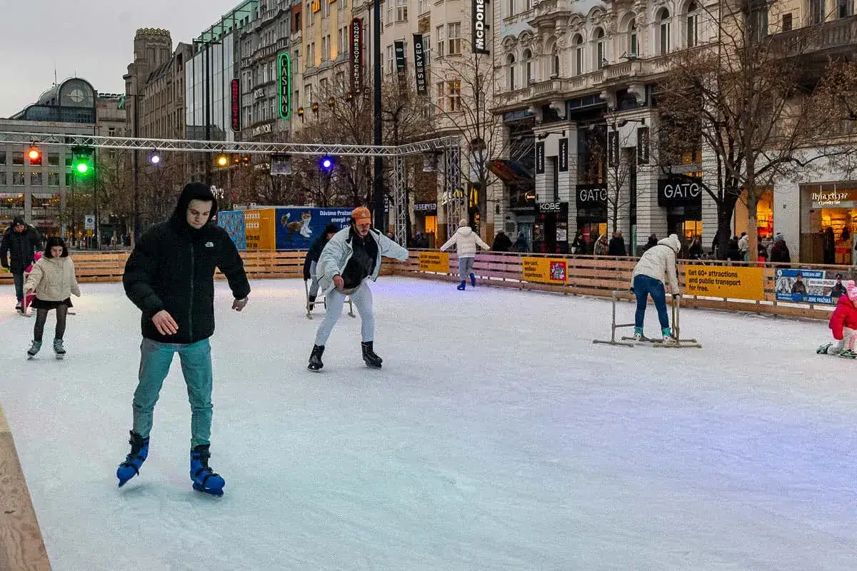 Patinage sur glace à Prague, des gens s'amusent sur la patinoire en plein air, entourés par l'architecture de la ville.