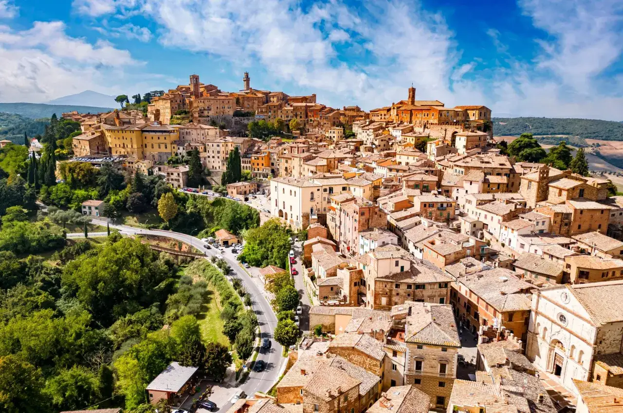 Vue a&eacute;rienne d'une ville toscane perch&eacute;e sur une colline, avec des toits de tuiles et des b&acirc;timents en pierre. Id&eacute;al pour savoir que faire en Toscane.