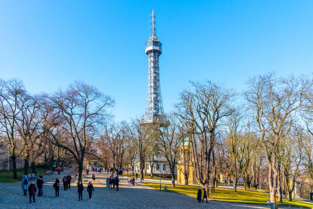 La tour Pétrin se dresse fièrement sous un ciel bleu, entourée d'arbres dénudés et de visiteurs profitant d'une promenade hivernale.