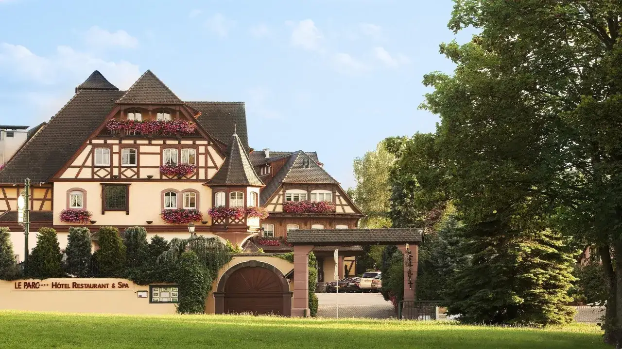 Le domaine du Moulin à Ensisheim, un hôtel restaurant & spa, s'offre sous un ciel bleu, entouré de verdure et de fleurs.