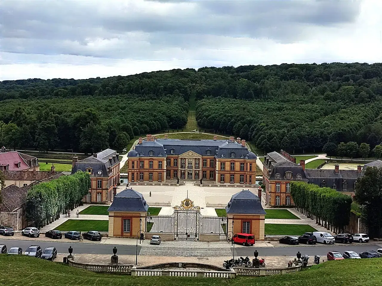 Vue aérienne d'un château majestueux, entouré de jardins et d'une forêt dense, évoquant la beauté de la vallée de Chevreuse.