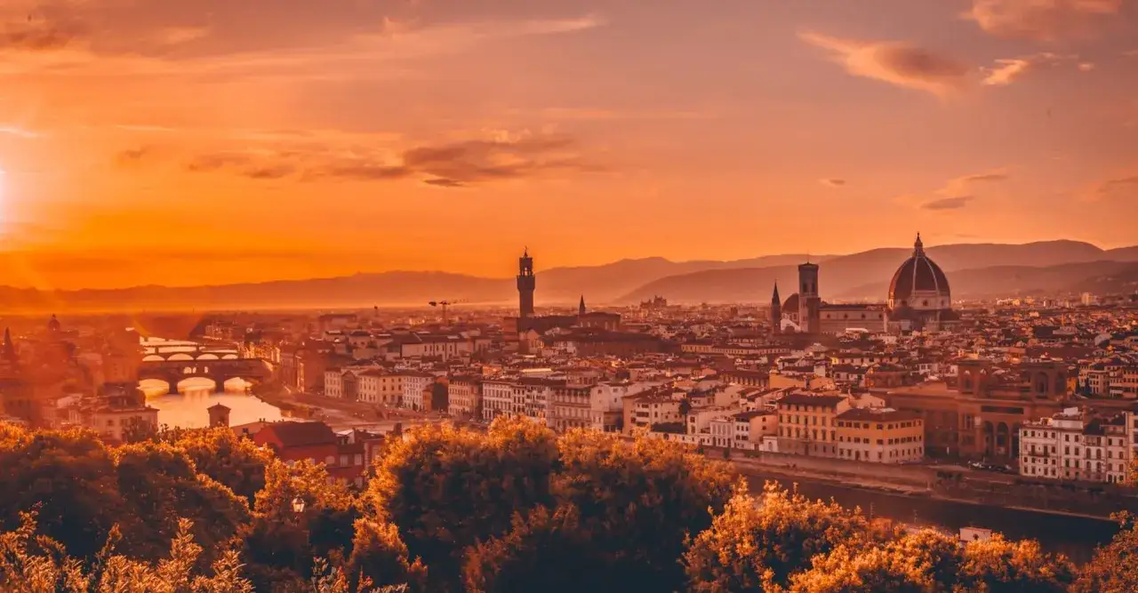 Vue panoramique de Florence au coucher du soleil depuis le Piazzale Michelangelo. La lumière dorée baigne la ville, révélant le Ponte Vecchio et le dôme de la cathédrale.