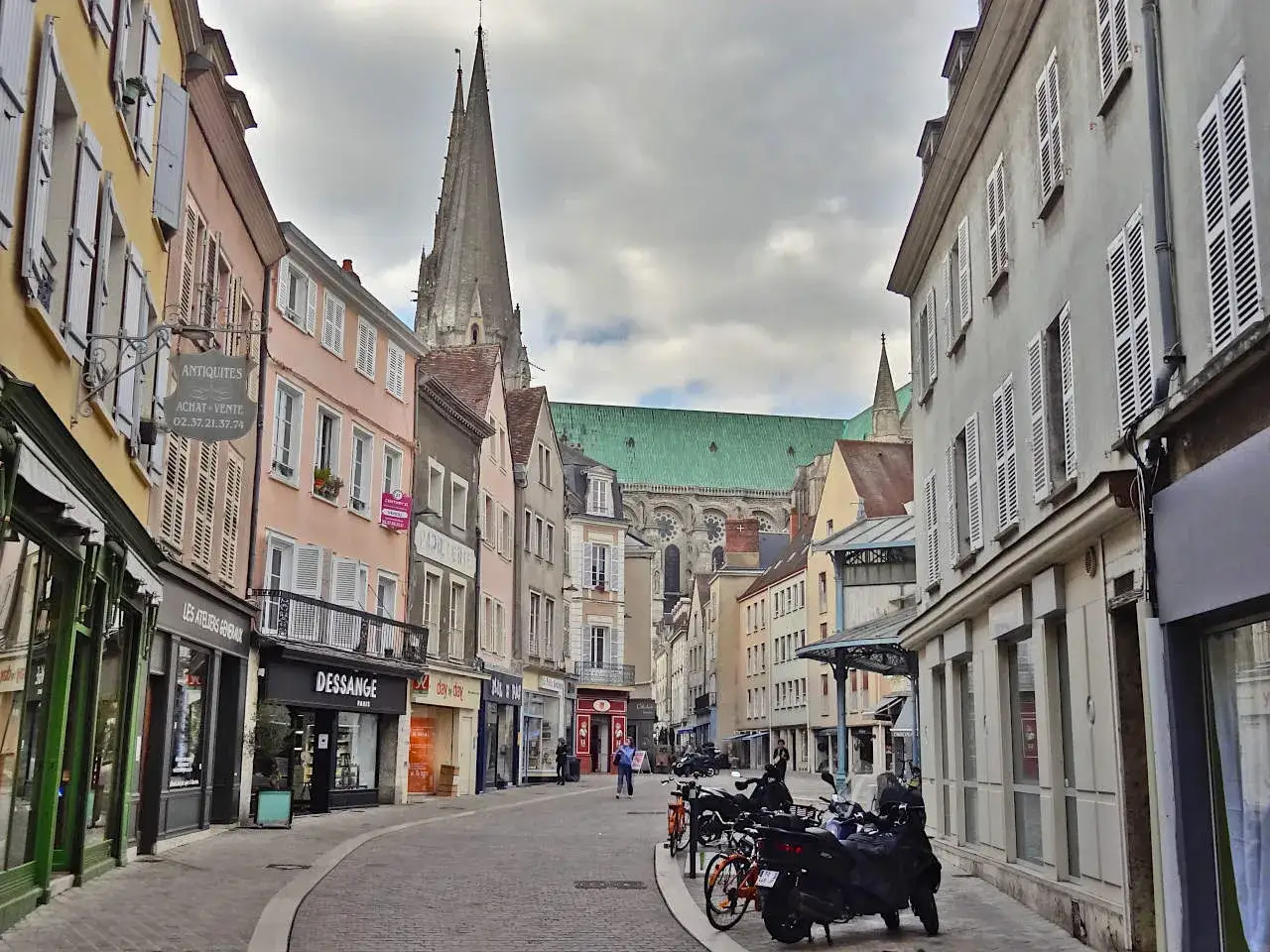 Une rue pavée mène à la cathédrale de Chartres. Idéal pour visiter Chartres à pied, avec ses boutiques et ses façades colorées.