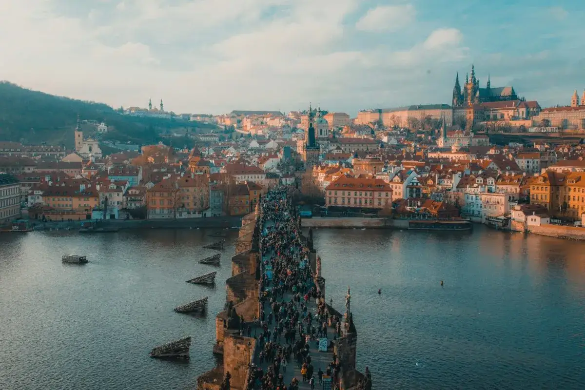 Vue du pont Charles bondé, une expérience incontournable pour visiter Prague en 1 jour. La ville s'étend à l'horizon, dominée par le château.