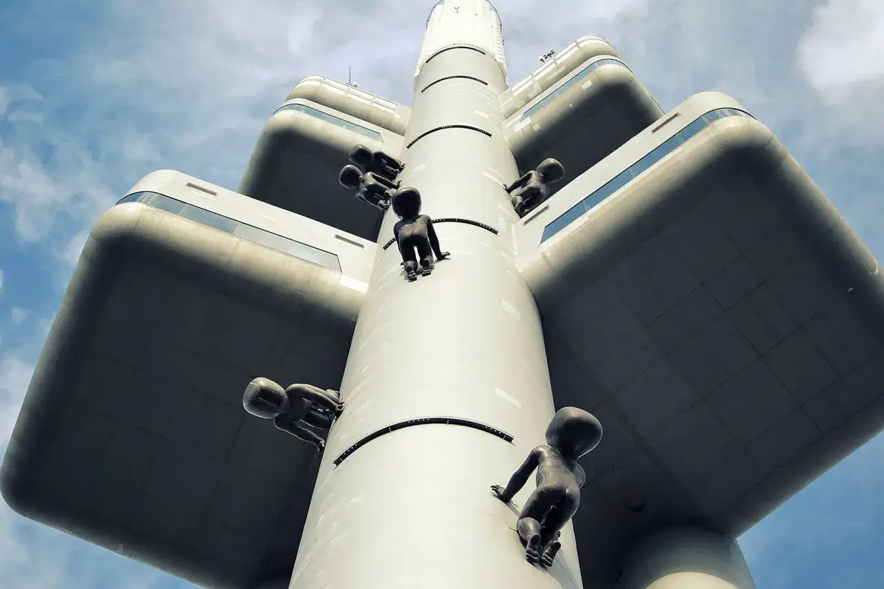 B&eacute;b&eacute;s escaladant la tour de t&eacute;l&eacute;vision, une sculpture insolite &agrave; Prague, d&eacute;fiant la gravit&eacute; sous un ciel bleu.