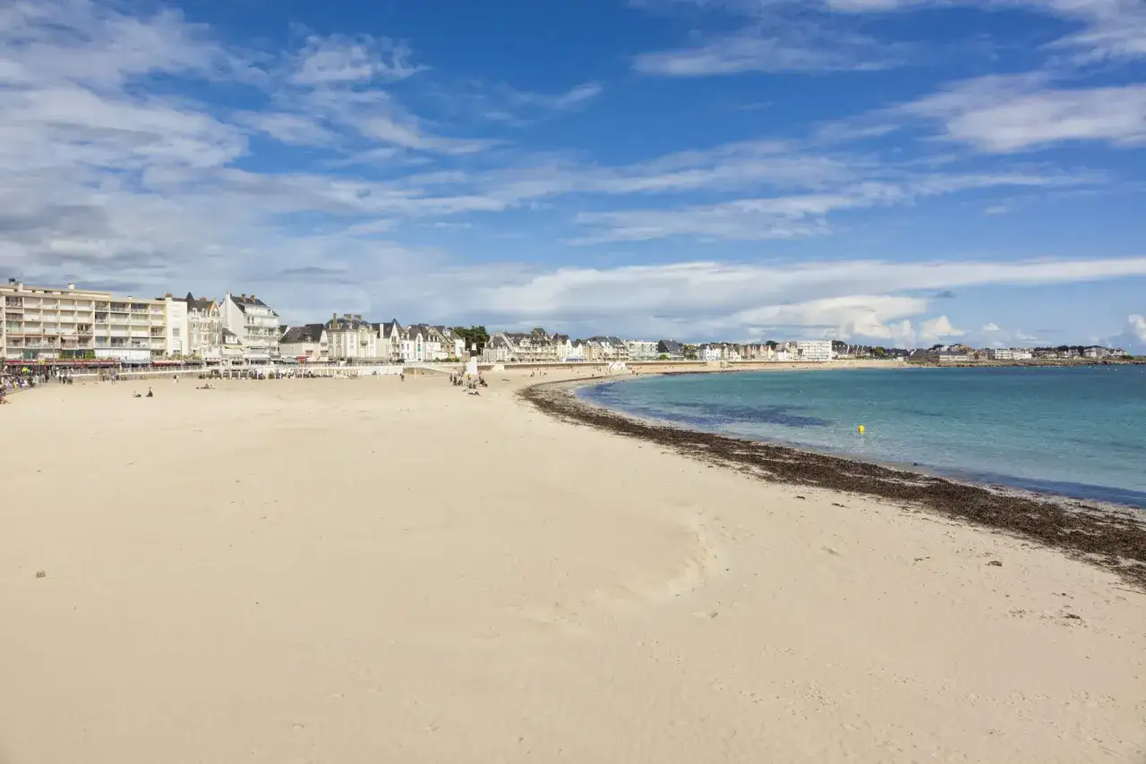 Plage de Quiberon, idéale pour savoir que faire à Quiberon ce week-end. Belles bâtisses en bord de mer, sable fin et mer bleue sous un ciel nuageux.