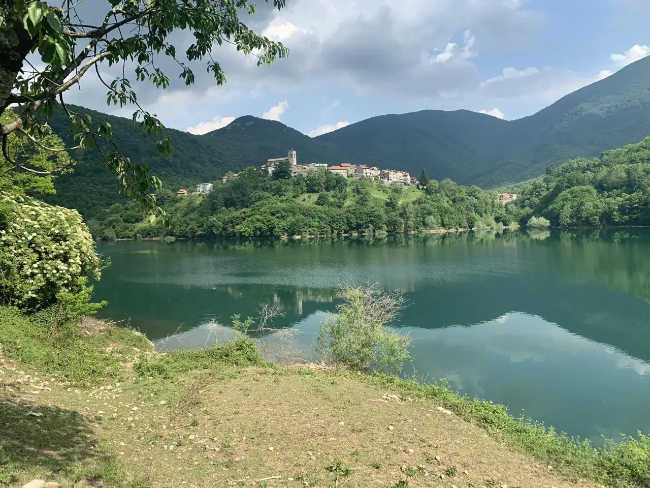 Vue paisible du lago di vagli, avec un village perch&eacute; sur une colline verdoyante.
