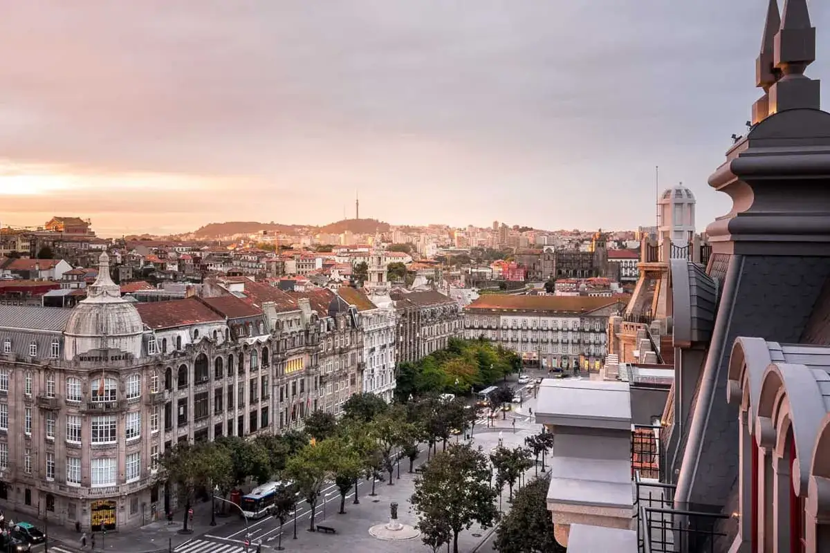 Vue panoramique d'une ville europ&eacute;enne au coucher du soleil, parfaite pour un city break. B&acirc;timents anciens, rues anim&eacute;es et ciel orang&eacute;.