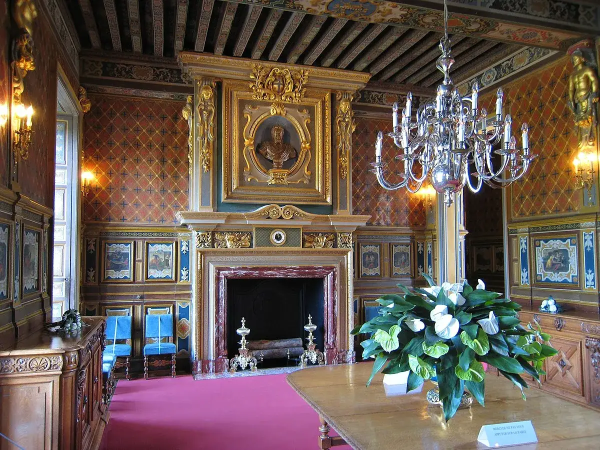 Intérieur luxueux du château de Cheverny, avec cheminée ornée, lustre étincelant et bouquet de fleurs sur une table.