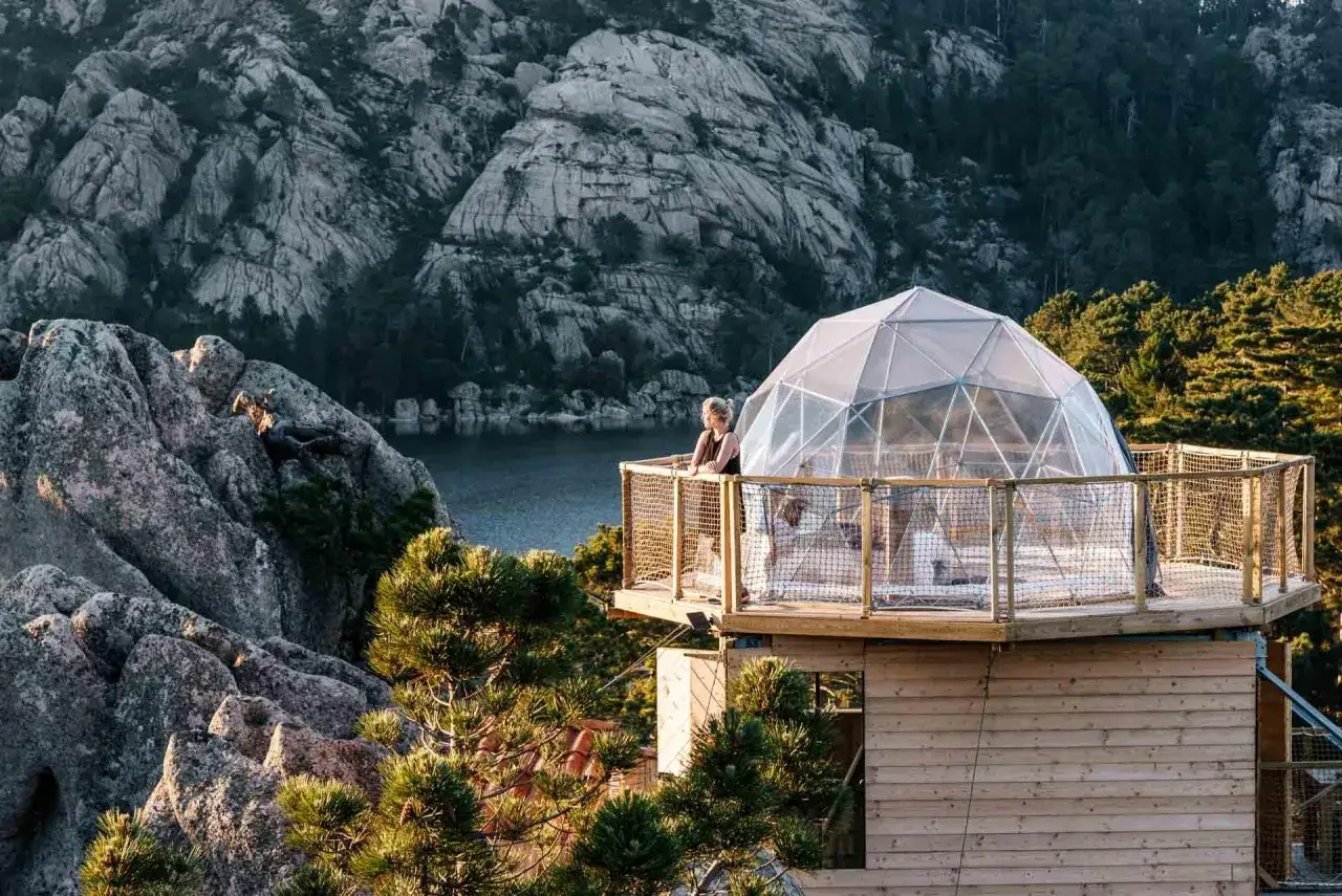 D&ocirc;me transparent sur pilotis, offrant une vue spectaculaire sur un lac et des montagnes rocheuses. Un exemple de lieux insolites dans le sud de la France.