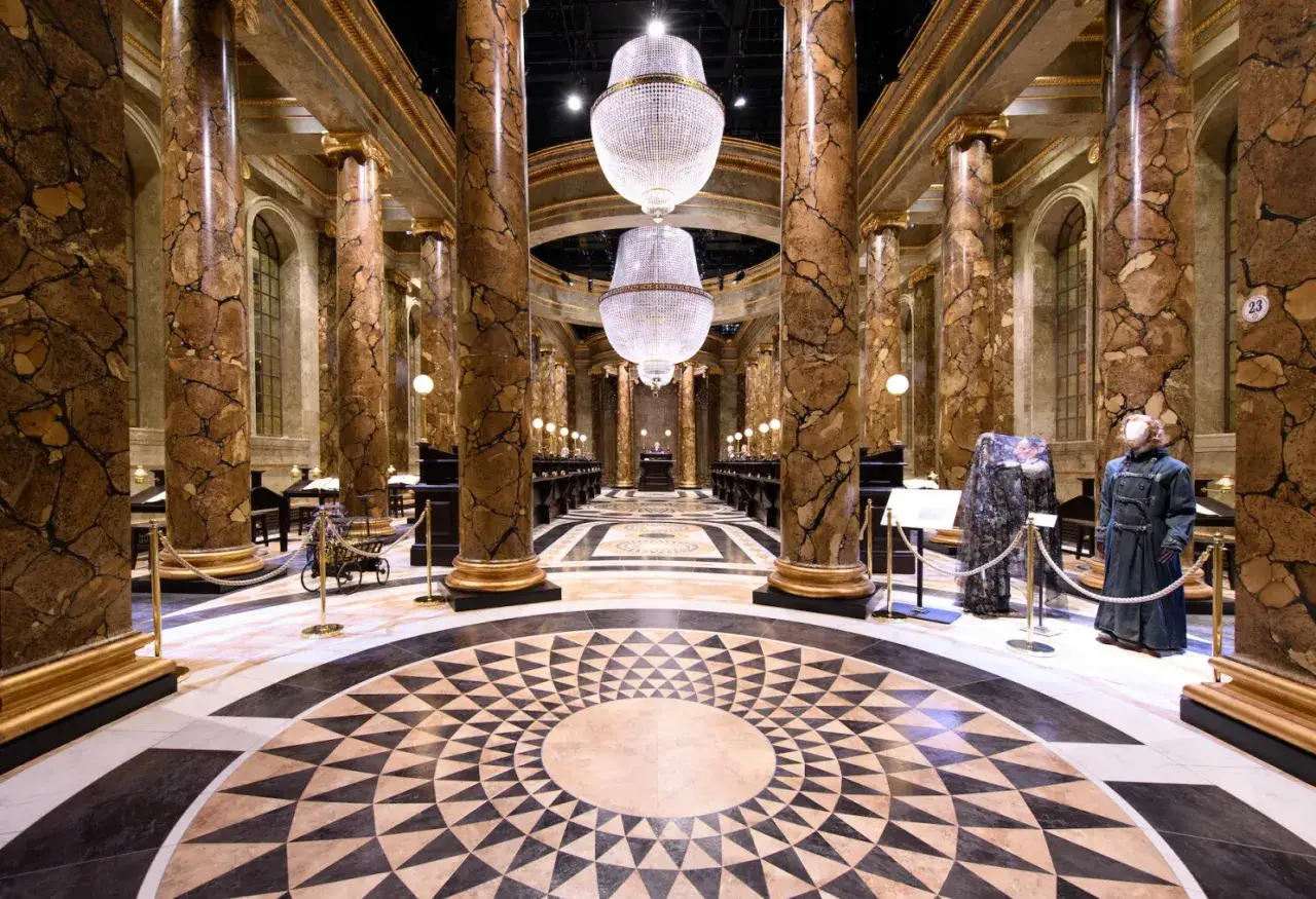 Le hall majestueux de la banque Gringotts, tel qu'on le voit au Harry Potter Studio, avec ses colonnes marbrées, ses lustres étincelants et son sol orné.