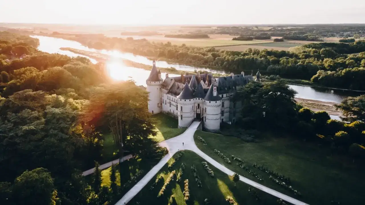 Le château de Chaumont-sur-Loire, baigné par le soleil couchant, se dresse majestueusement au bord de la Loire, entouré de verdure.